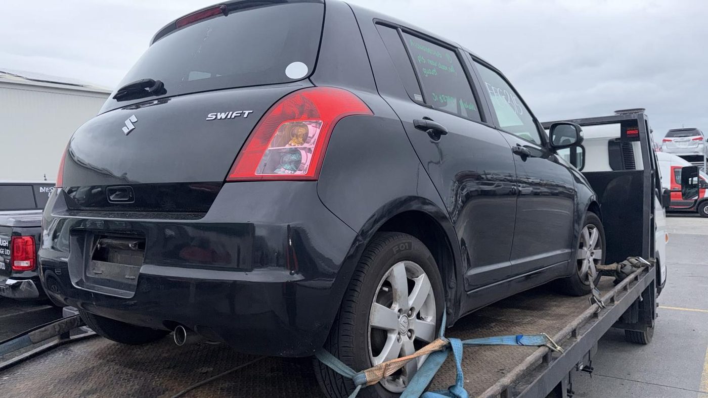 Black Suzuki Swift strapped onto a tow truck being collected in Ashburton